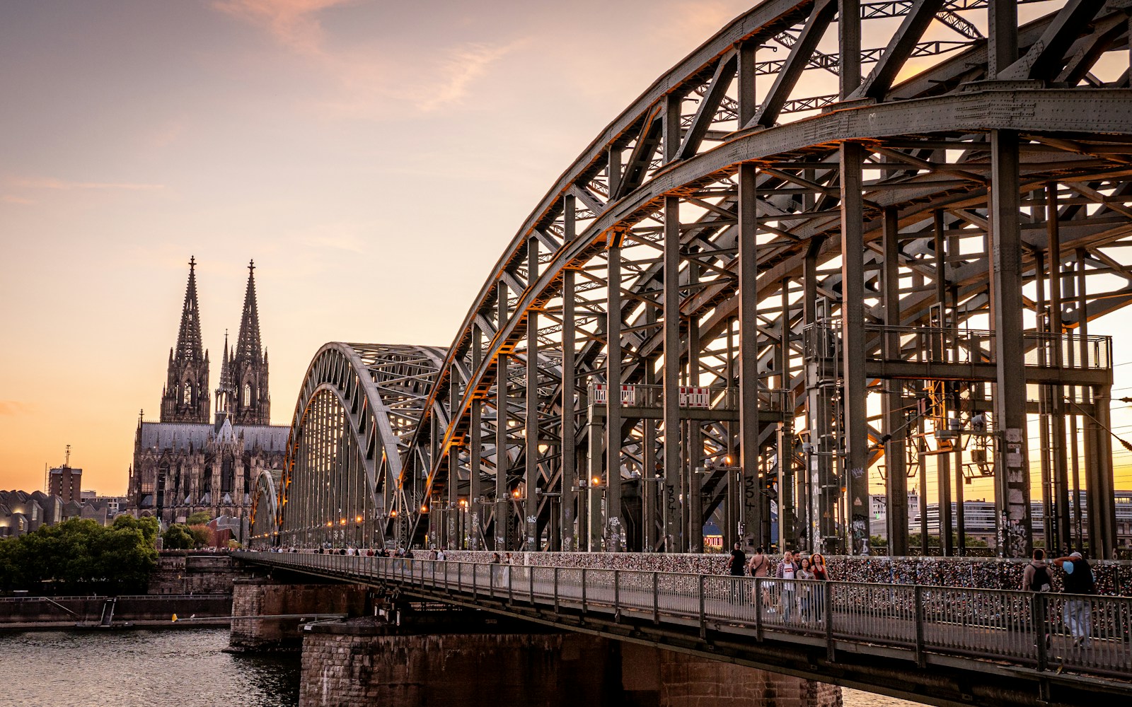 Steel bridge spans river with cathedral in background
