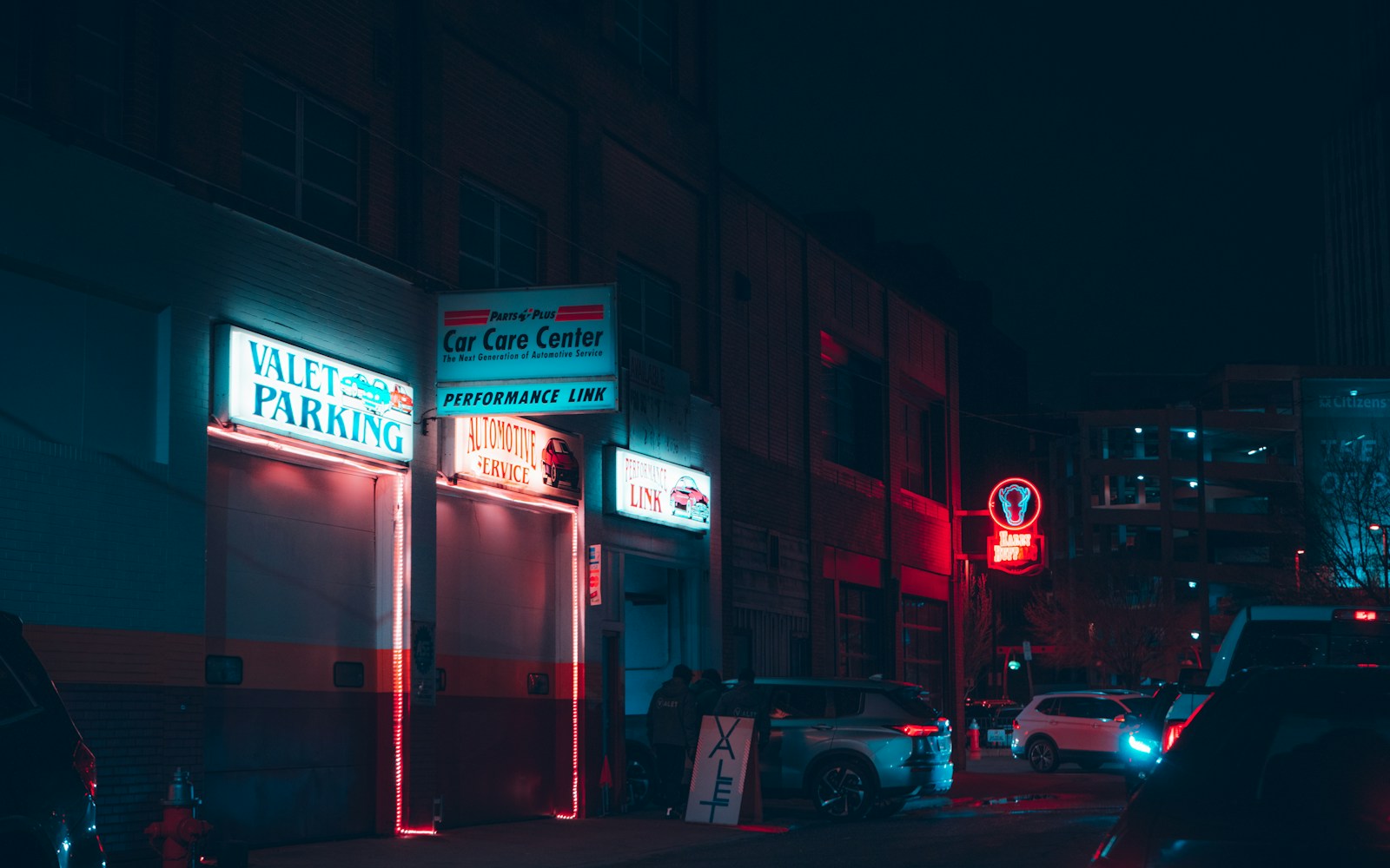 a city street at night with cars parked on the side of the street